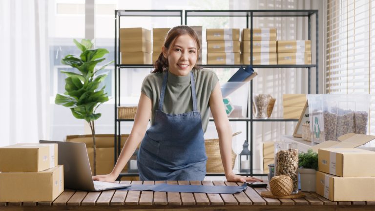 smiling small business owner with laptop and phone