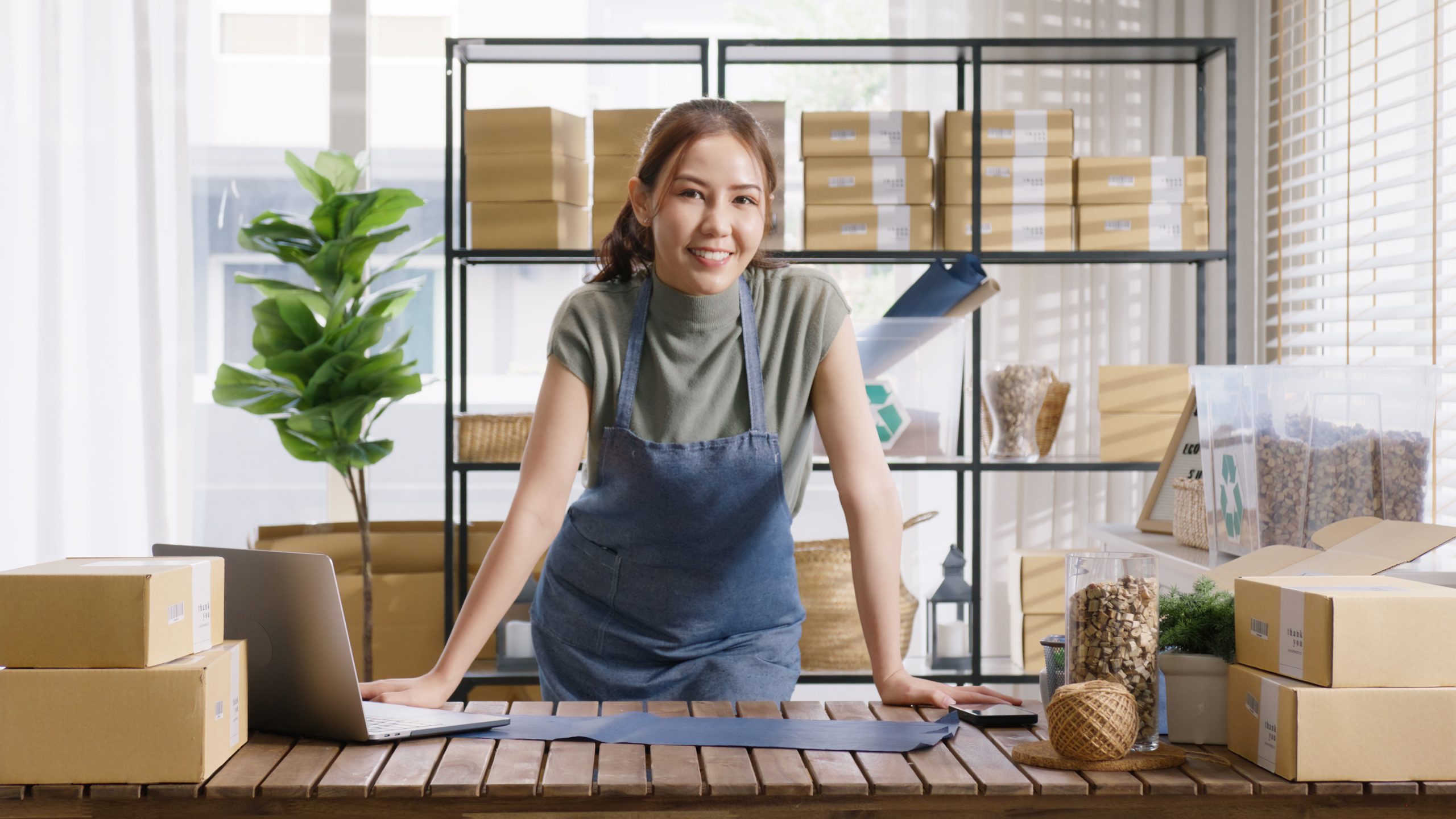 smiling small business owner with laptop and phone